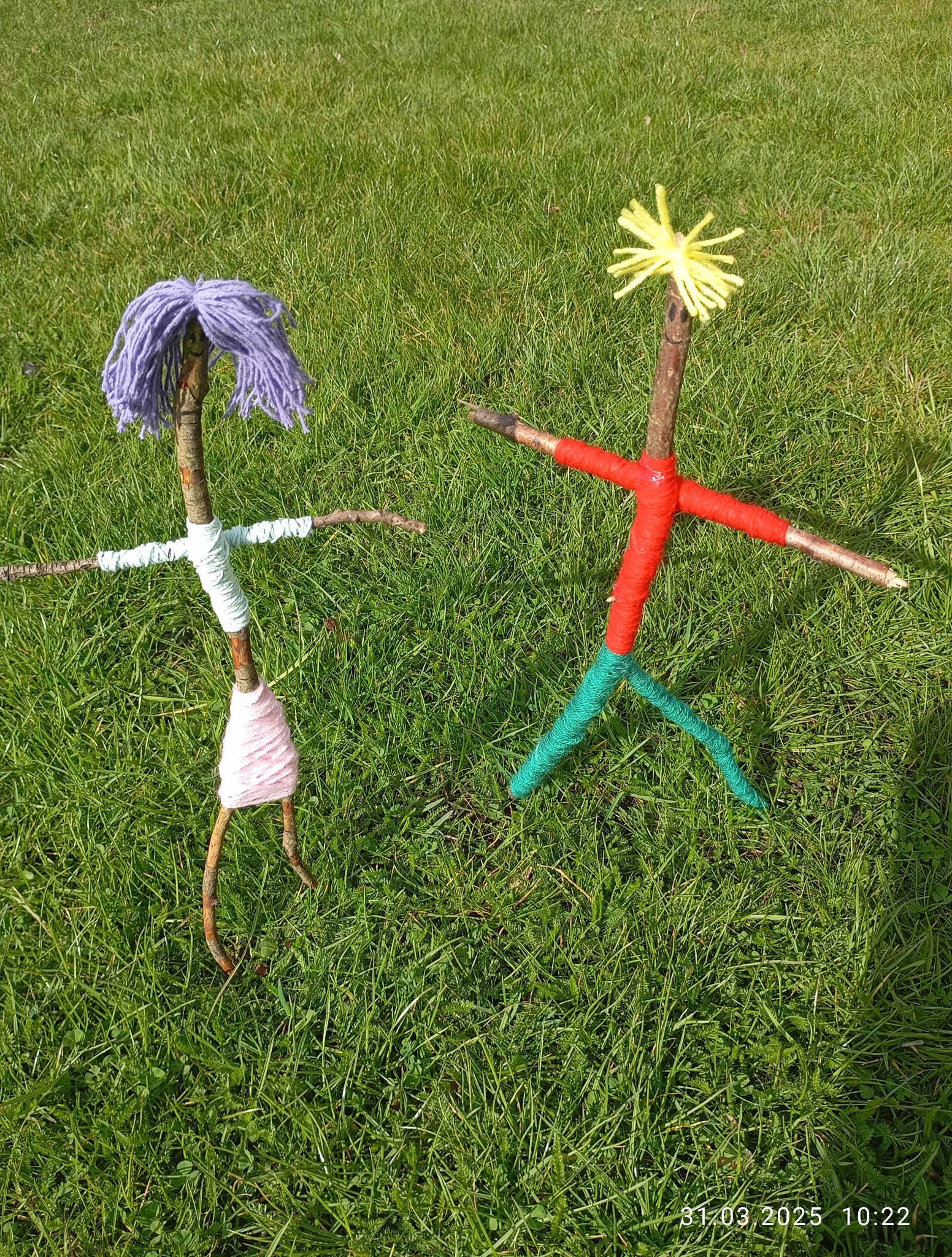 Ręcznie robione kukiełki z gałązek i włóczki na trawie w Toruniu. Kreatywne ozdoby dla dzieci, idealne na animacje i zabawy plenerowe. Dekoracje na przyjęcie.