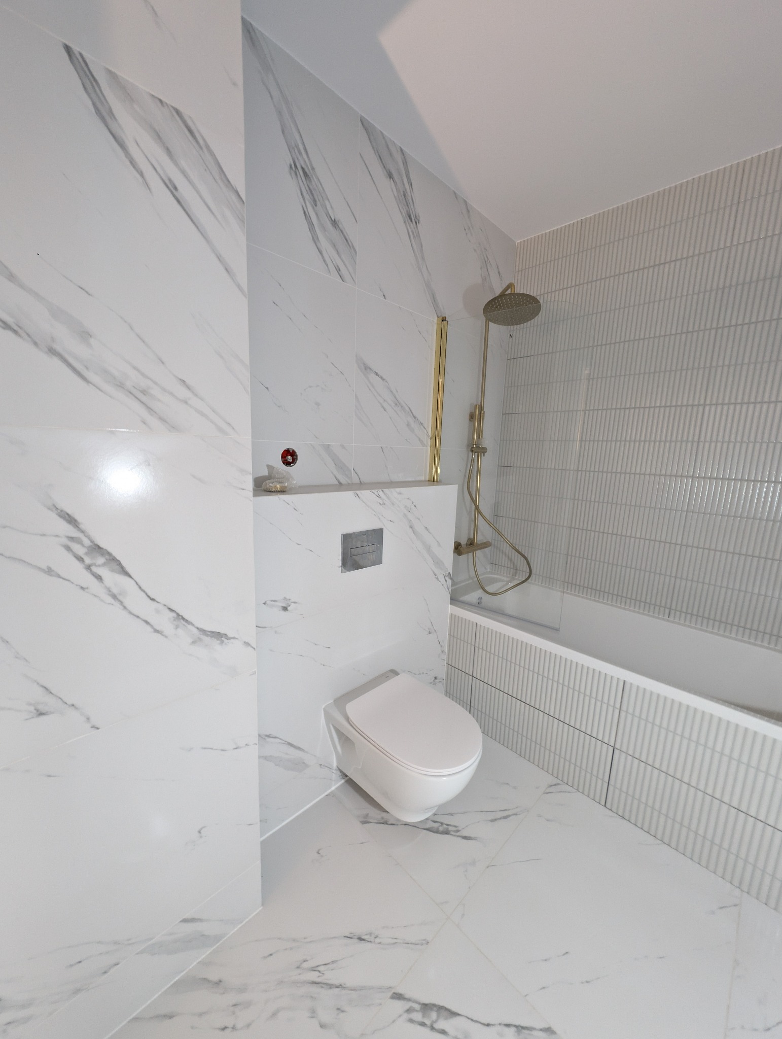Nowoczesna łazienka w bieli: marmurowe płytki, podwieszana toaleta i złota armatura prysznicowa. Minimalistyczny design z subtelnymi akcentami kolorystycznymi.
