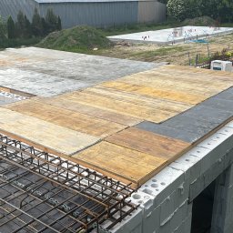 Motix - Budowa domu: ściany z betonu komórkowego, szalunek stropu z desek i płyty, zbrojenie. W tle fundamenty kolejnego budynku.