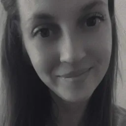 Portret uśmiechniętej kobiety z długimi włosami w czerni i bieli. Wyraźne oczy i delikatny uśmiech. Neutralne tło.