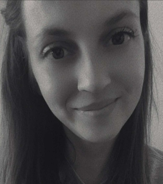 Portret uśmiechniętej kobiety z długimi włosami w czerni i bieli. Wyraźne oczy i delikatny uśmiech. Neutralne tło.