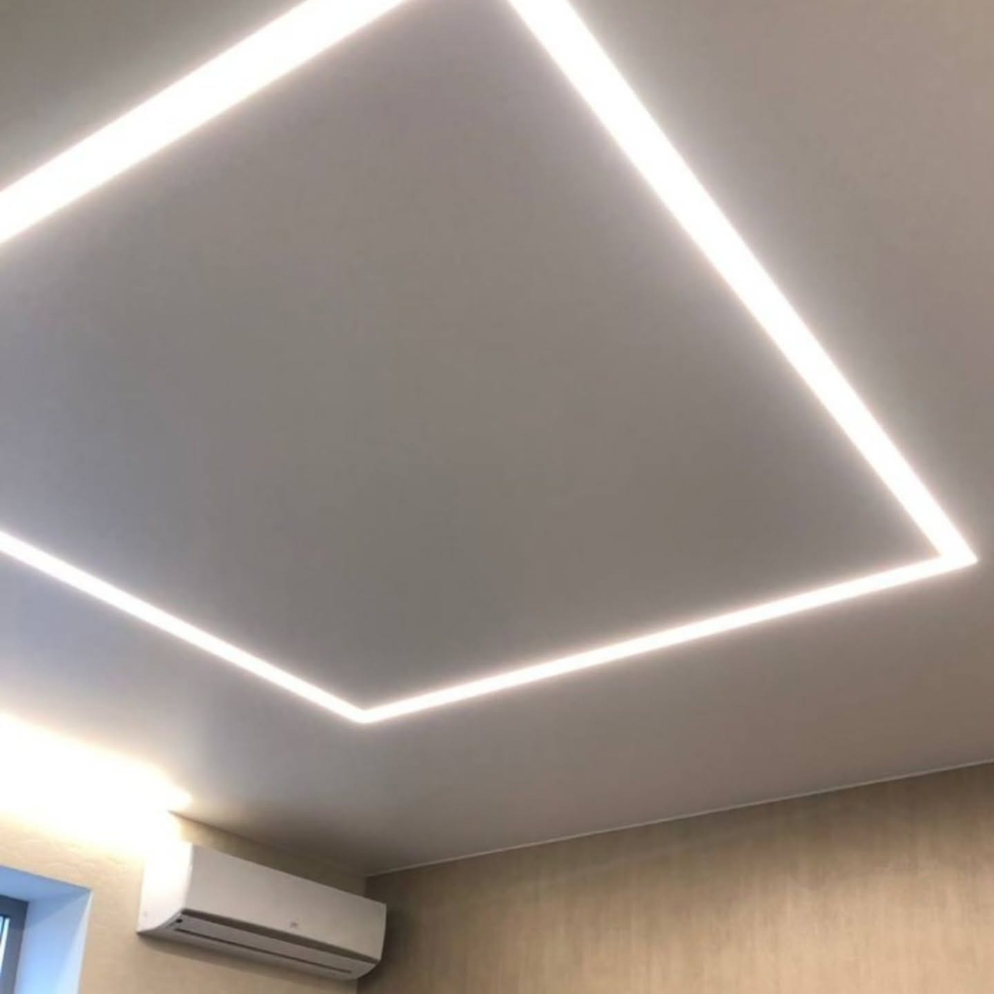 Nowoczesne oświetlenie sufitowe LED w kształcie kwadratu, z klimatyzacją na ścianie. Minimalistyczny design wnętrza z równomiernym, jasnym światłem.