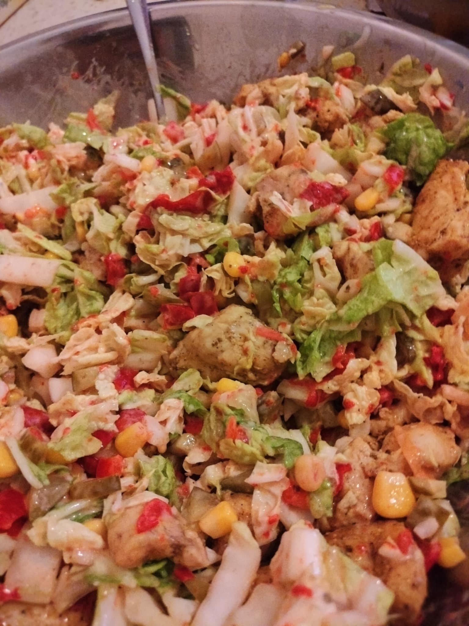 Świeża sałatka warzywna z kawałkami kurczaka w metalowej misce, widok z góry, idealna na catering firmowy lub świąteczny.