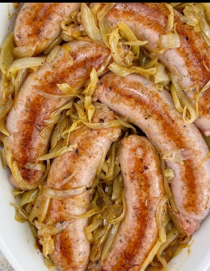 Apetyczne, grillowane kiełbaski otoczone karmelizowaną cebulą, gotowe do serwowania w Pile. Idealne danie na firmowy obiad lub świąteczny stół.