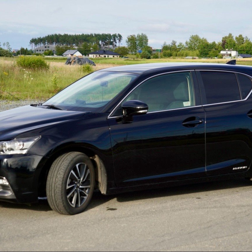 Czarne auto z przyciemnionymi szybami na tle krajobrazu. Widoczne odbicia w karoserii. Efekt przyciemniania szyb.