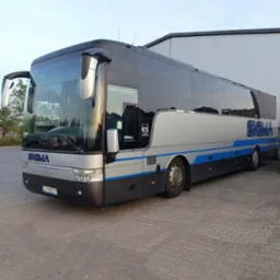 Srebrno-czarny autokar SIGMA z niebieskimi akcentami, zaparkowany na brukowanym placu, widok z boku, tablica rejestracyjna LCH-80577, budynek w tle.