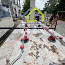 MeryArt Home - Przygotowanie wielkoformatowych płyt z kamienia naturalnego do montażu, z użyciem specjalistycznych narzędzi z przyssawkami, na tle budynku w trakcie wykończenia.