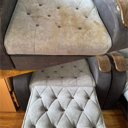 Vitalii Romanchuk - Kadr fotela z widocznymi plamami na siedzisku, zestawiony z czystym pufem w tym samym stylu. Widoczne drewniane podłokietniki i pikowane wykończenie.