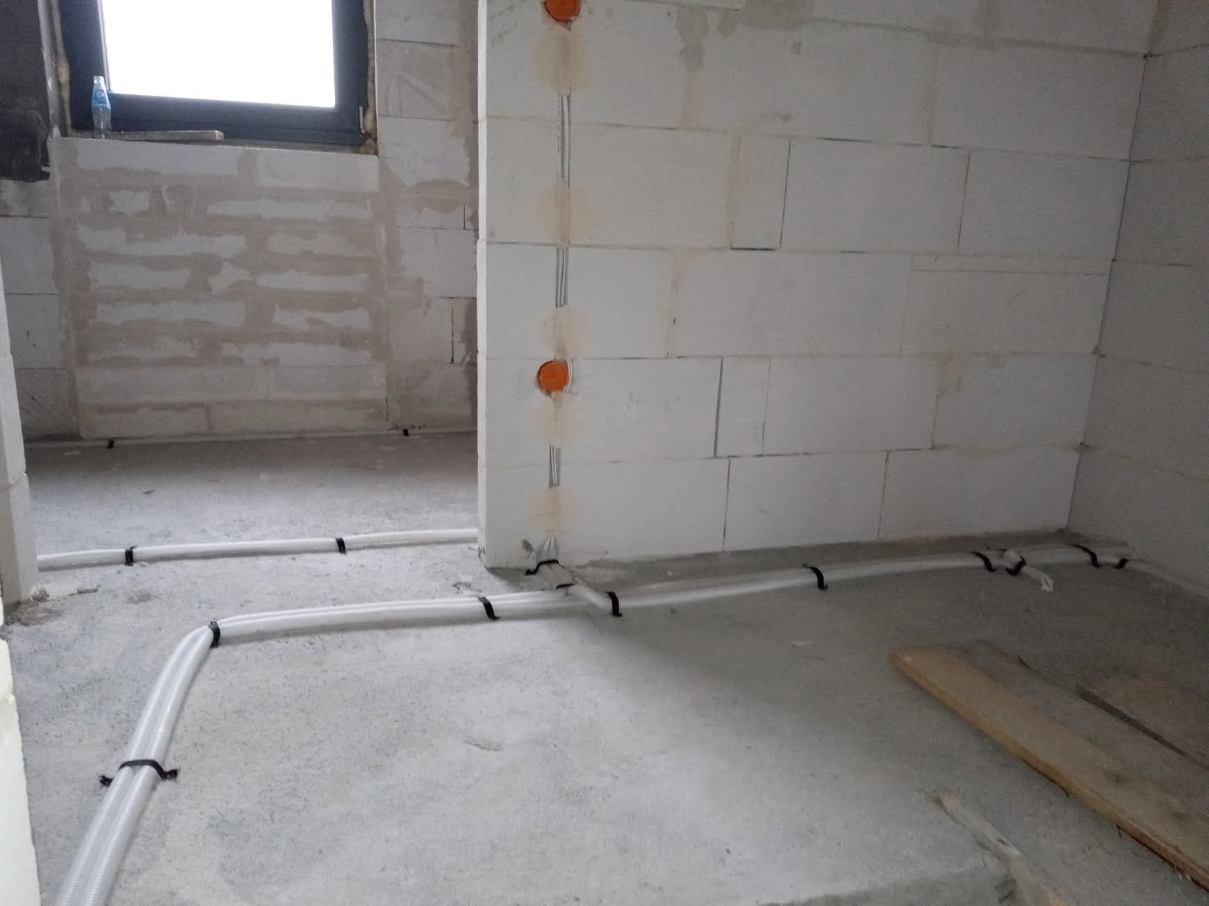 Wewnętrzna instalacja elektryczna w rurkach karbowanych, zamocowanych do podłoża w surowym stanie. Widoczne puszki elektryczne w ścianie z betonu komórkowego.