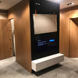 BluMeble - Nowoczesna zabudowa RTV z drewnianymi frontami i czarnym panelem. Podwieszana szafka RTV w kolorze białym. Białe płótno zawieszone na klipsach.