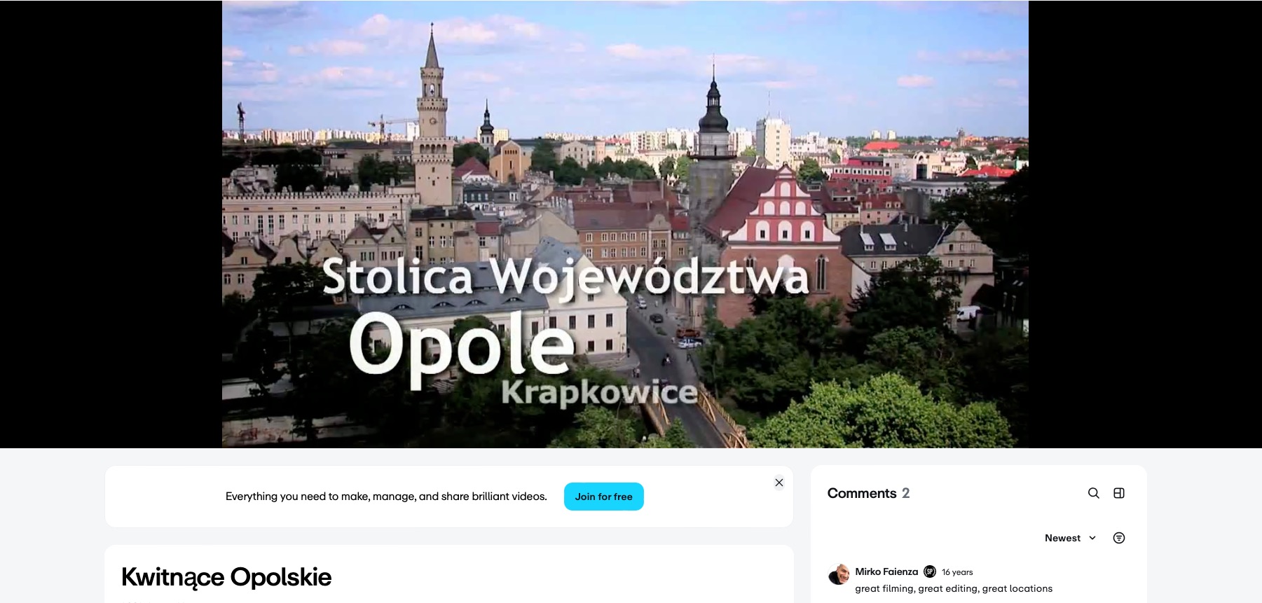 Panorama Opola z charakterystyczną wieżą ratuszową i czerwonym kościołem w tle, ukazana w słoneczny dzień. Ujęcie z lekkiej perspektywy.