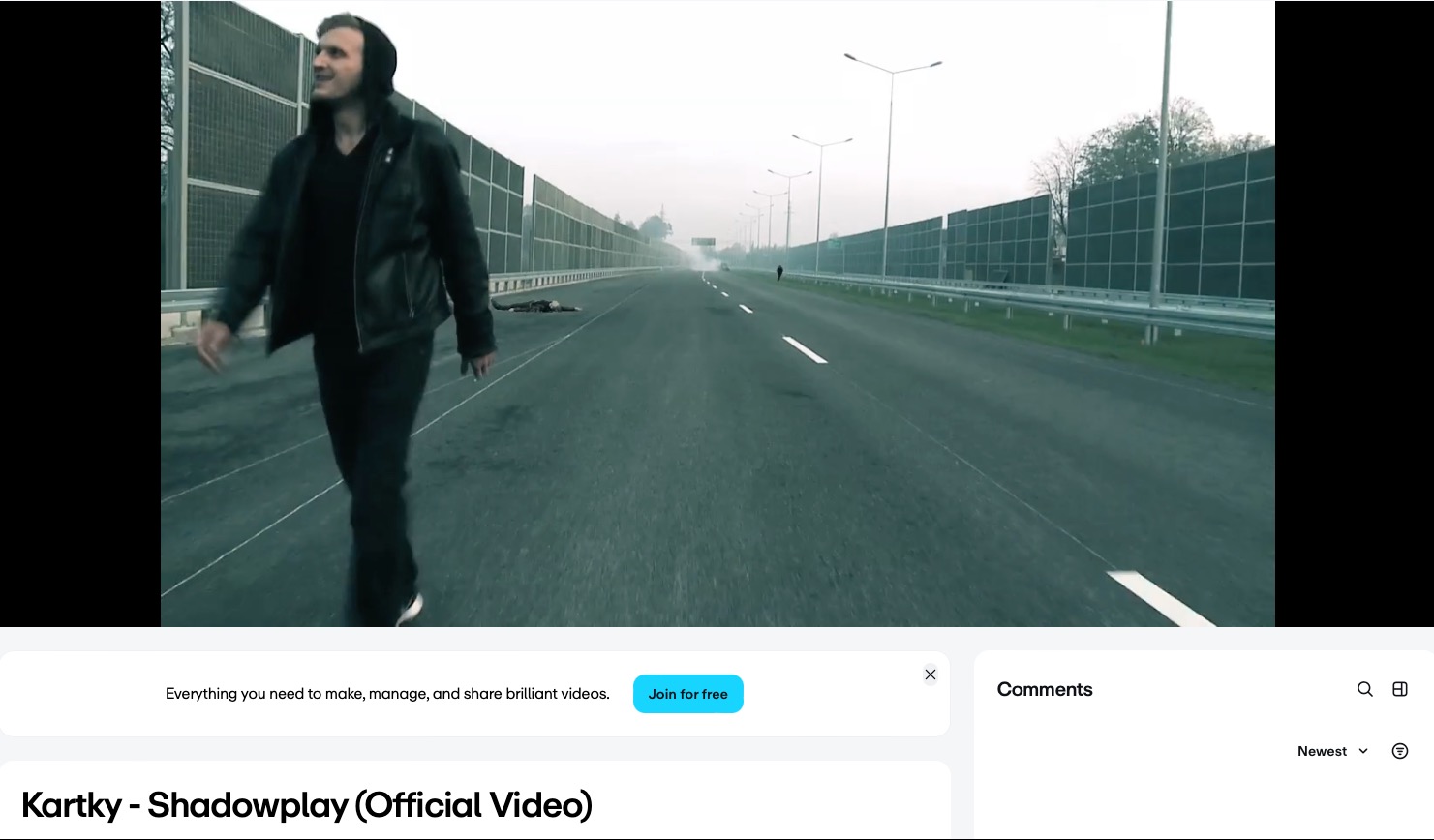 Ujęcie z planu filmowego: mężczyzna w czerni idzie po autostradzie, w tle leżące osoby i oddalający się samochód. Atmosfera tajemniczości i napięcia, chłodna kolorystyka.