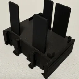 Czarny, plastikowy model z pionowymi elementami, widoczne warstwy druku, na jasnym tle. Model wykonany metodą addytywną, z widoczną teksturą warstw.