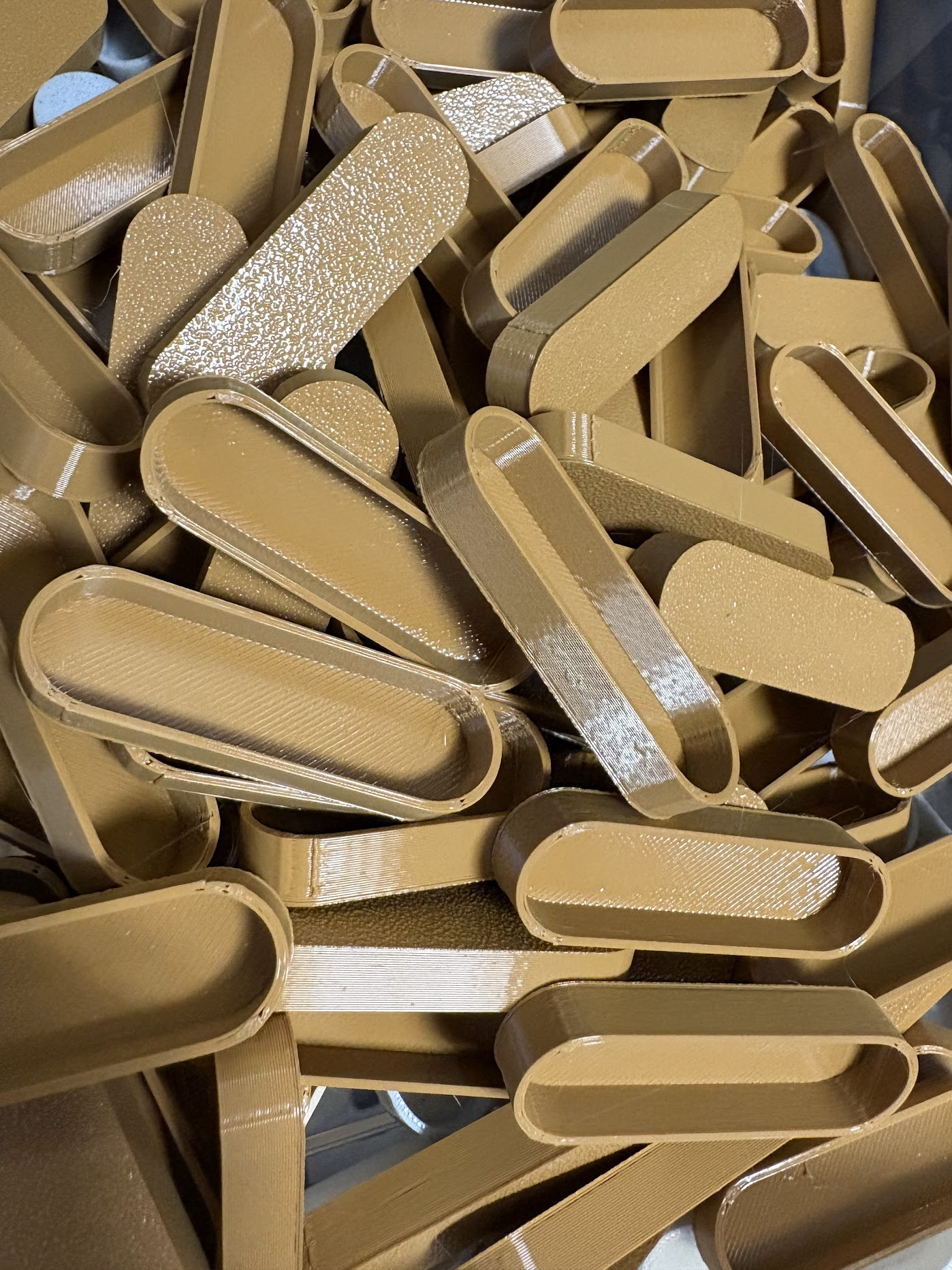 Beżowe, owalne ramki ułożone chaotycznie, widoczne ślady warstwowego druku, różne faktury powierzchni.