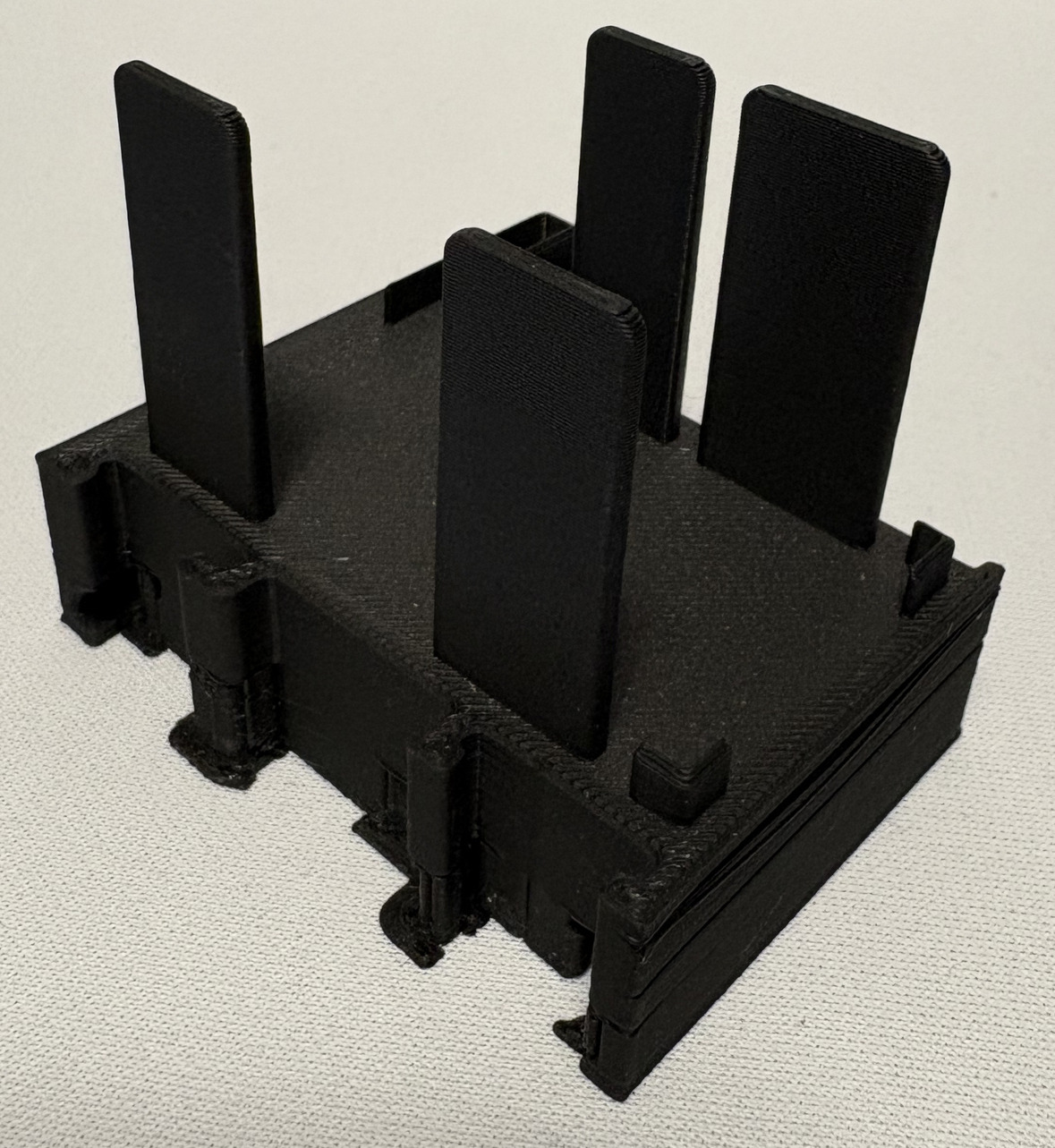 Czarny, plastikowy model z pionowymi elementami, widoczne warstwy druku, na jasnym tle. Model wykonany metodą addytywną, z widoczną teksturą warstw.