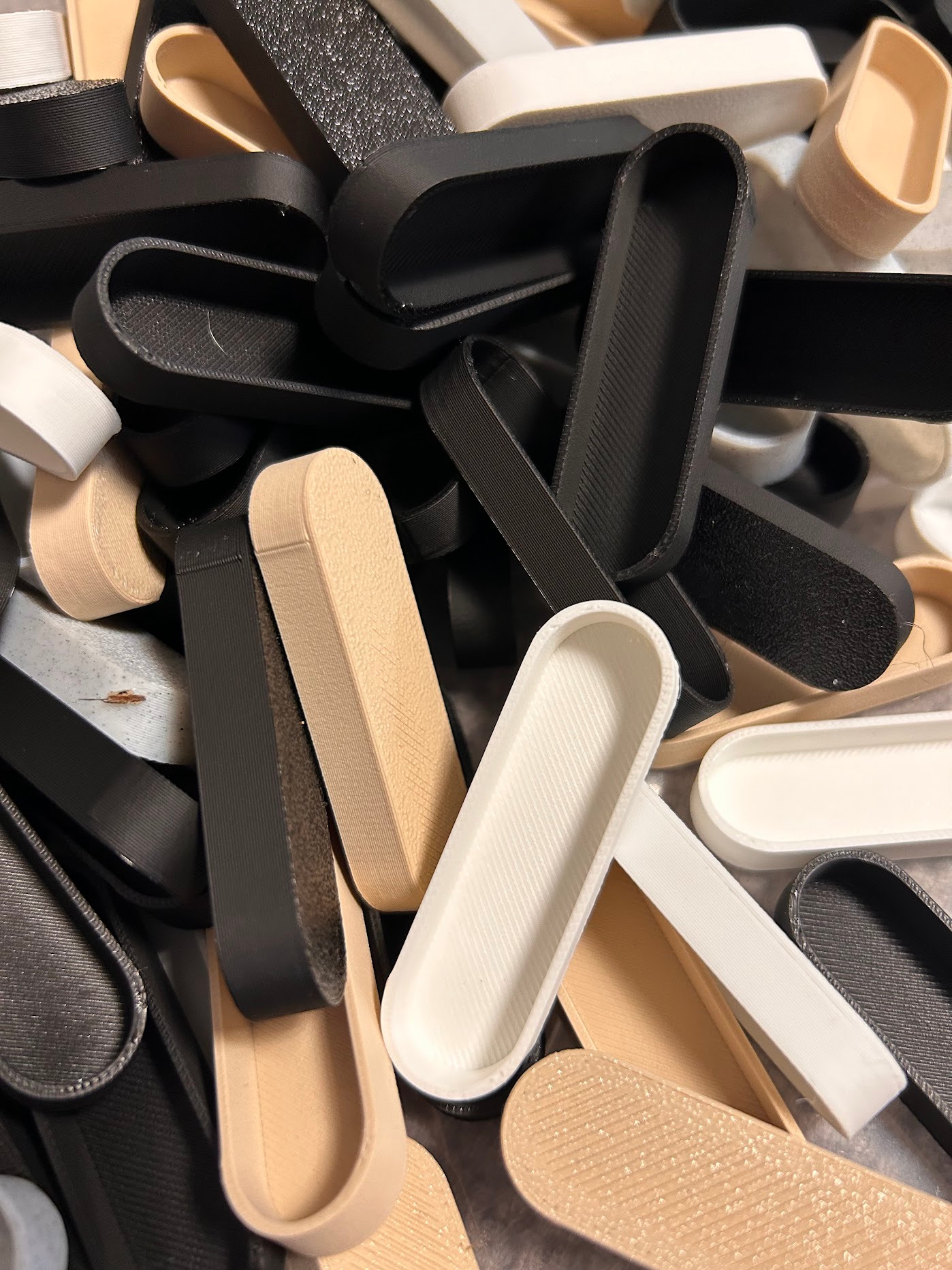 Stos wydrukowanych, owalnych elementów w odcieniach bieli, beżu i czerni. Widoczna charakterystyczna tekstura warstwowa, sugerująca proces druku.