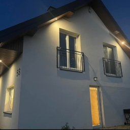 XTEAM - Oświetlenie zewnętrzne domu z numerem 55 w Katowicach, z lampami punktowymi pod okapem, widok nocą.