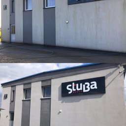 PH Daniel Hoppa - Budynek przed i po czyszczeniu elewacji, widoczna różnica w czystości ściany z szyldem 'Stuba Meble' oraz kostki brukowej. Wąż ciśnieniowy na ziemi.