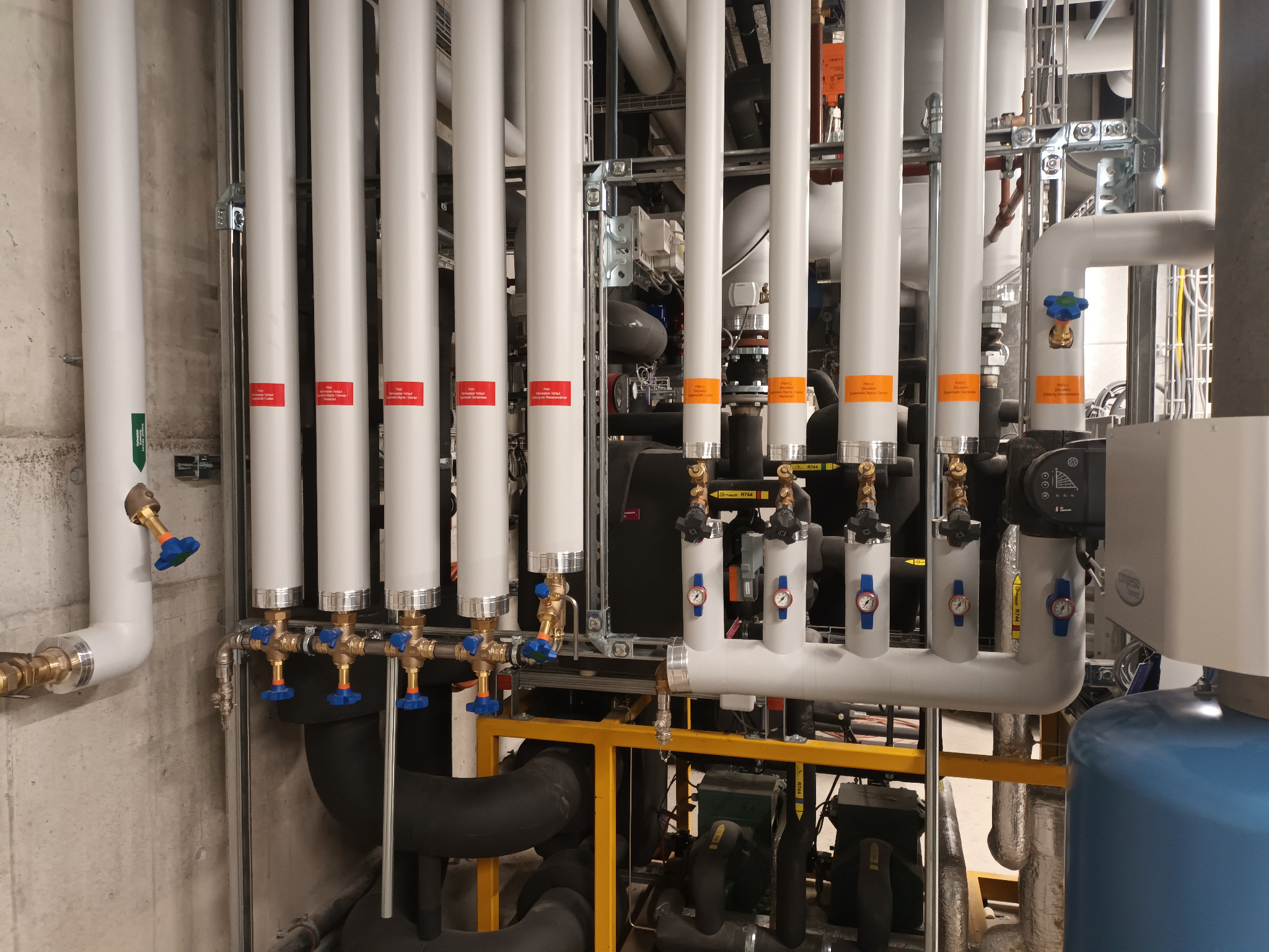 Kompleksowa instalacja rur w kotłowni z licznymi zaworami i oznaczeniami, widoczne elementy kotła i konstrukcja wsporcza. Precyzyjny montaż instalacji.