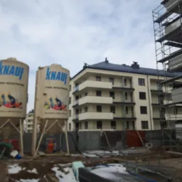 Zbiorniki Knauf Tynki Maszynowe na placu budowy nowego budynku wielorodzinnego, widoczne rusztowania.