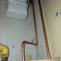 Gazownik-Gdańsk - Zamontowany gazomierz z nową instalacją z rur miedzianych. Żółty zawór gazowy po lewej stronie. Ściana z widocznymi śladami po instalacji.