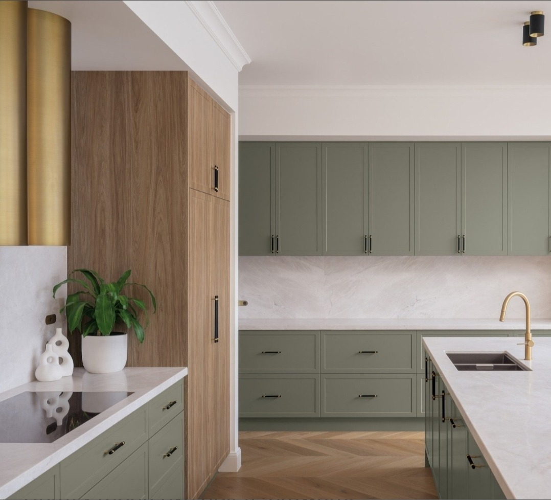Stylowa, nowa kuchnia w odcieniach zieleni z drewnianymi akcentami. Marmurowy blat i złota armatura dodają elegancji. Widoczny fragment parkietu w jodełkę.