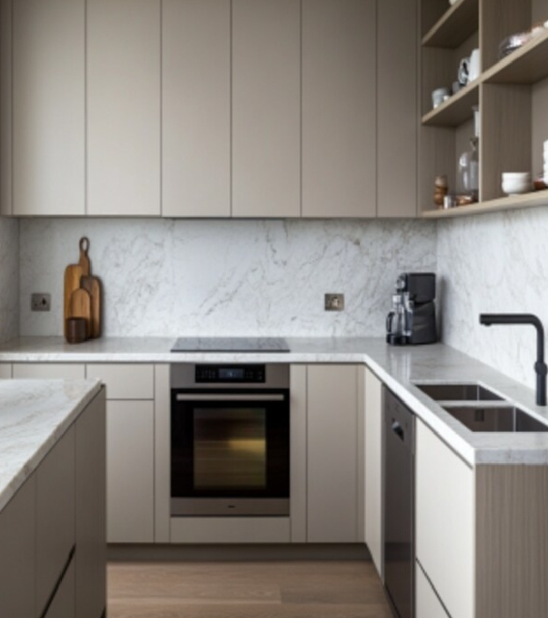 Nowoczesna kuchnia w beżowych tonacjach z marmurowym blatem i backsplashiem. Minimalistyczne szafki, czarna armatura i drewniane akcenty. Widoczne deski do krojenia.