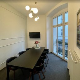 Kancelaria Rozwodowa - Adwokat Weronika Hołowczyc - Sala konferencyjna z długim, czarnym stołem i czarnymi krzesłami. Na ścianie telewizor i obraz. Duże okno z widokiem na zewnątrz.