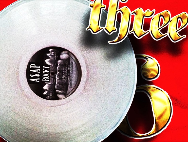 Okładka srebrnej płyty winylowej A$AP Rocky na czerwonym tle z napisem 'Three' w złotym kolorze, częściowo zasłaniającym płytę.