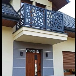 Usługi spawalnicze Arkadiusz Mika - Nowoczesna, ażurowa balustrada balkonowa w geometryczne wzory, zamontowana na jasnej elewacji domu z drewnianą stolarką okienną i drzwiami wejściowymi.