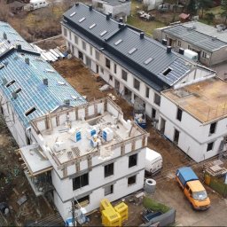 LEVEL Michał Wójcicki - Wysoki kąt: budowa kompleksu budynków w różnym stanie ukończenia, z widocznymi elementami konstrukcyjnymi i materiałami budowlanymi, oraz pojazdami.