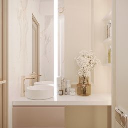 GAMKO+PARTNERS Sp. z o.o. - Beżowa łazienka z marmurowymi ścianami, okrągłą umywalką i złotą armaturą. Na blacie kosmetyki i wazon z drobnymi białymi kwiatami. Lustro z podświetleniem LED.