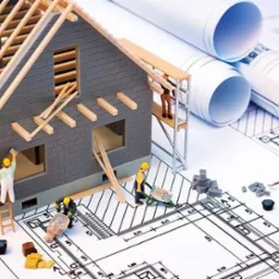 Miniaturowy model domu w trakcie budowy, otoczony przez miniaturowe figurki robotników, narzędzia i zwinięte plany, całość na tle architektonicznym.