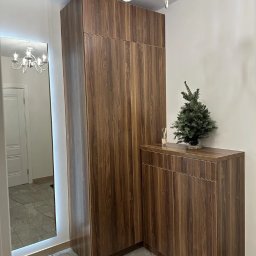 ROBOTA & PLUS - Szafa wnękowa z lustrem w przedpokoju, wykończona okleiną w kolorze ciemnego drewna. Oświetlenie LED wokół lustra i marmurowe płytki podłogowe.