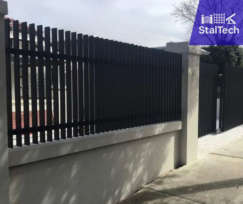Nowoczesne, czarne ogrodzenie metalowe z pionowych sztachet, osadzone na betonowym murku, z widocznym logo firmy StalTech w prawym górnym rogu.