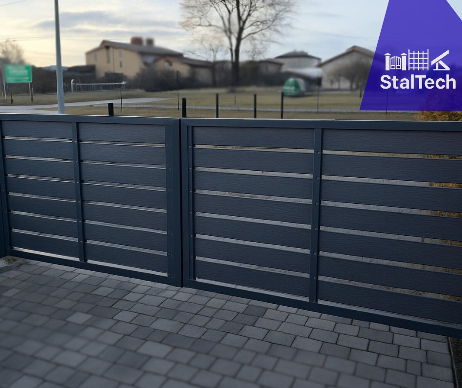 Nowoczesna brama wjazdowa kompozytowa w kolorze grafitowym z poziomymi panelami, na tle kostki brukowej i zabudowań mieszkalnych. Widoczne logo producenta.