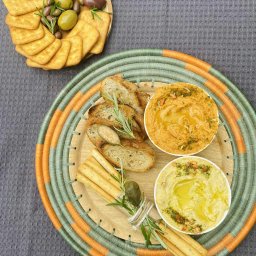 Szef Kuchni Poleca - Dekoracyjna taca z przekąskami: hummus, pieczywo, grissini, oliwki i krakersy. Elegancki catering na imprezę w Łomiankach, gotowy do serwowania.