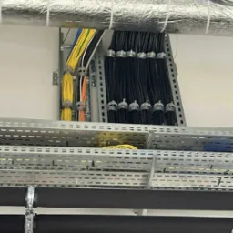 Profesjonalnie ułożone kable elektryczne w korytach i na drabinkach kablowych, z widoczną izolacją termiczną rur. Estetyczny montaż instalacji.