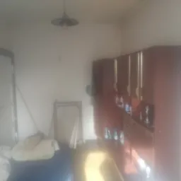 Pokój przed sprzątaniem w Szczecinku: niepościelone łóżko, ciemne meble, nieporządek. W tle widoczna rama lustra.