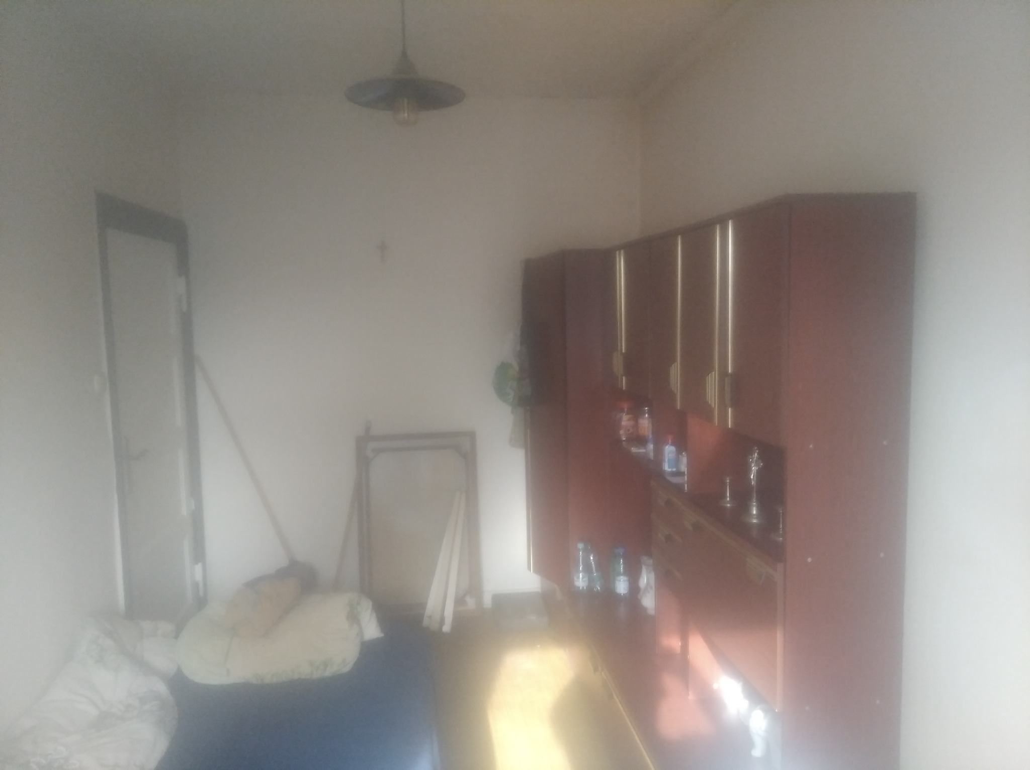 Pokój przed sprzątaniem w Szczecinku: niepościelone łóżko, ciemne meble, nieporządek. W tle widoczna rama lustra.