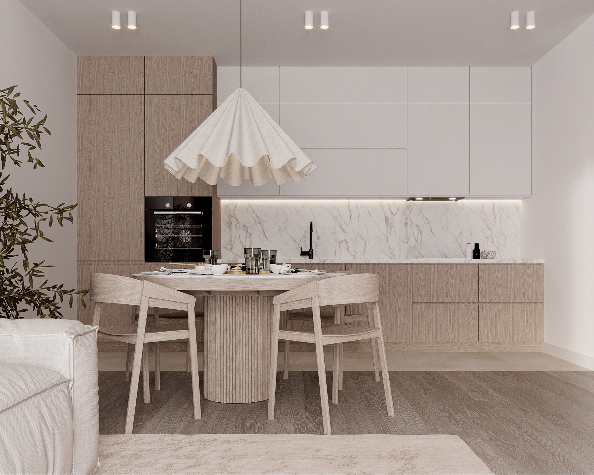 Jasna kuchnia z drewnianymi szafkami i marmurowym blatem. Okrągły stół z krzesłami i dekoracyjna lampa. Minimalistyczny design z rośliną doniczkową w rogu.