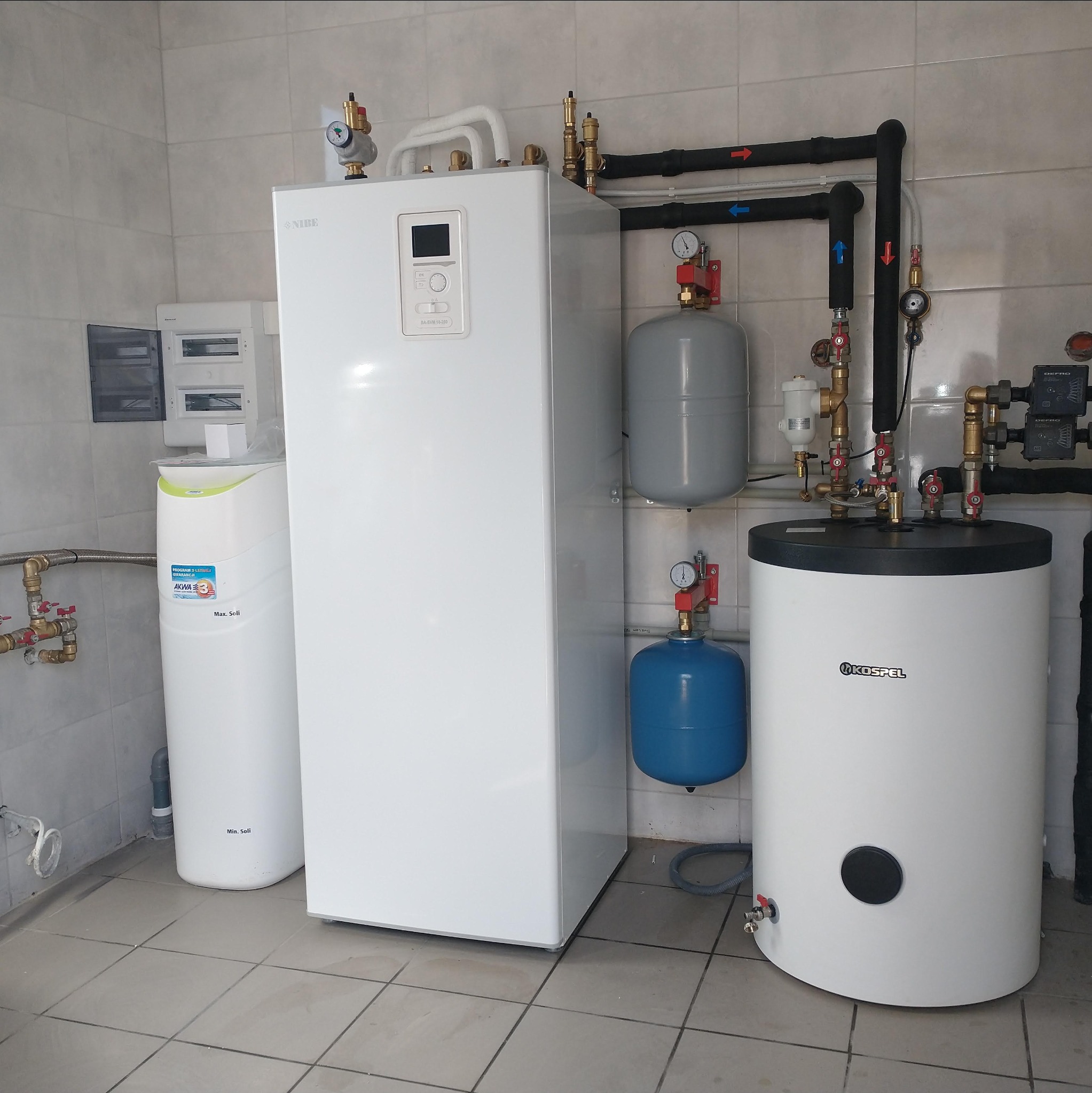 Kompleksowa instalacja grzewcza z pompą ciepła Nibe i zasobnikiem Kospel w kotłowni w Strawczynie. Widoczne rury, zawory i osprzęt.