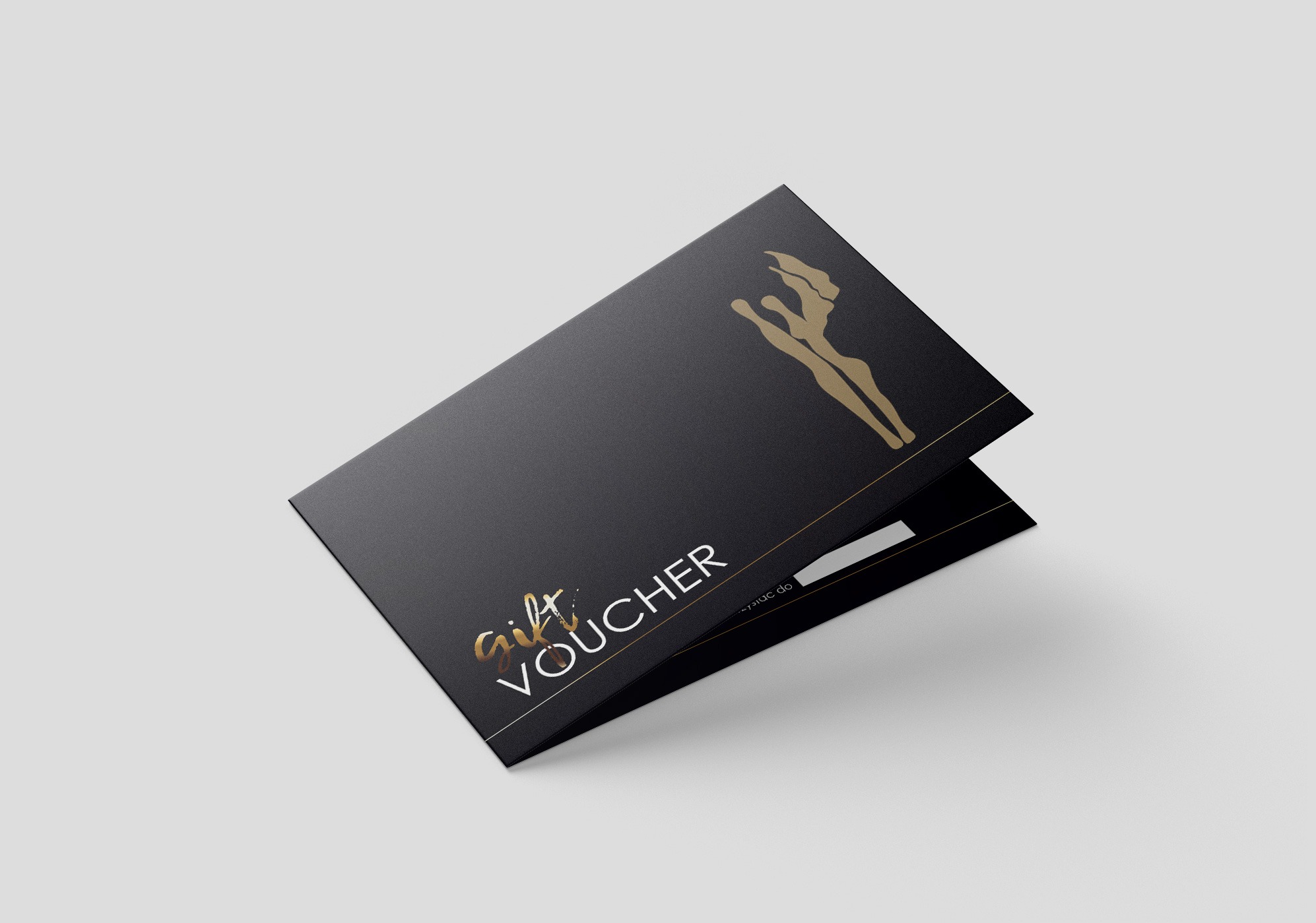 Elegancki, otwarty voucher prezentowy w czerni ze złotymi akcentami i logo, leżący na jasnym tle. Minimalistyczny design, widoczny fragment kodu rabatowego.