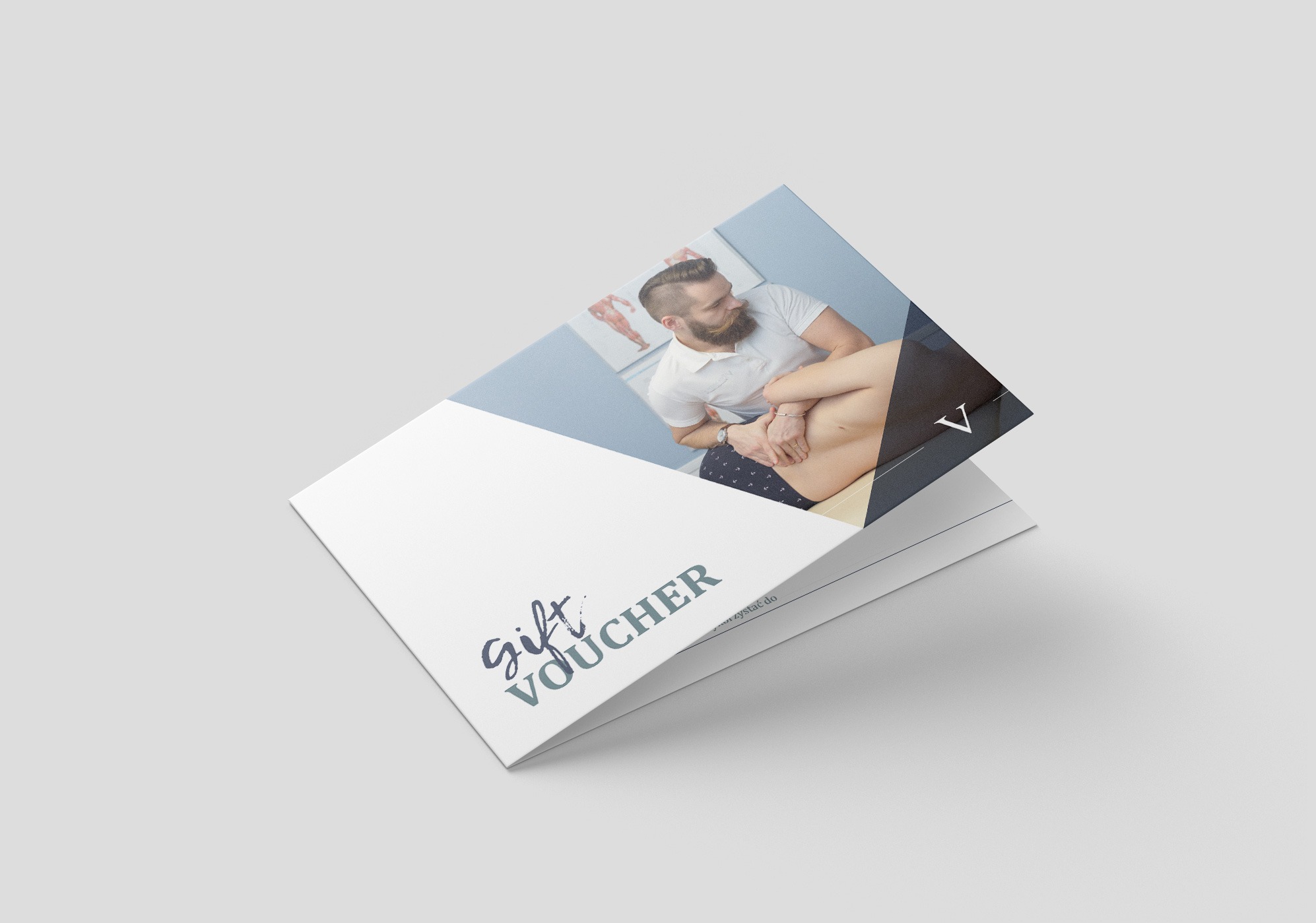 Elegancki voucher prezentowy z grafiką masażu na okładce, leżący ukośnie na jasnym tle. Widoczne logo i napis 'gift voucher' w odcieniach granatu. Minimalistyczny design.