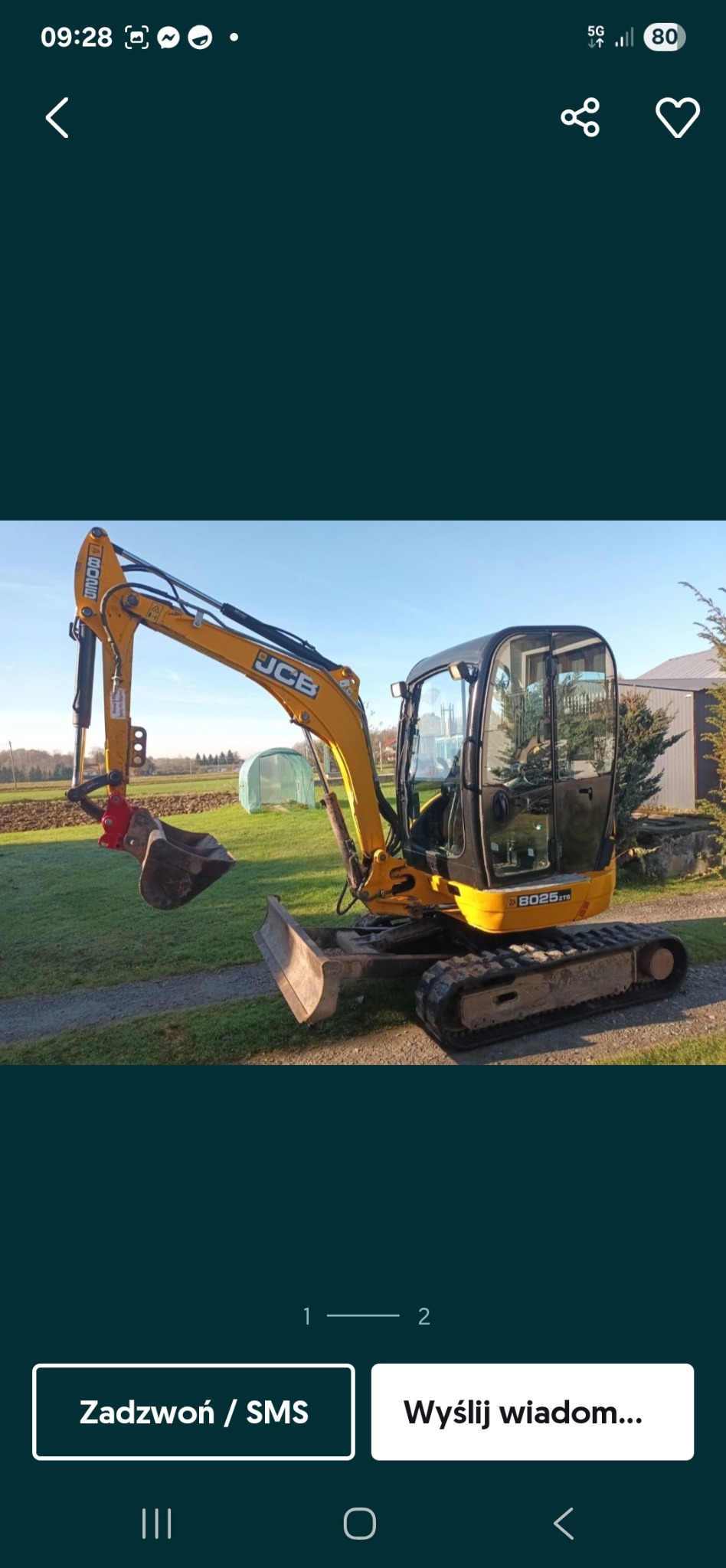 Żółta koparka JCB 8025 ZTS z łyżką i lemieszem na trawiastym terenie, widoczny szklarnią w tle. Sprzęt gotowy do pracy.