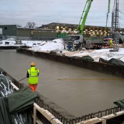 Zbrójstal Sp. z o.o. - Wylewanie betonu na przygotowany fundament w zimowych warunkach. Widoczny pracownik w odblaskowej kamizelce i pompa do betonu w tle.