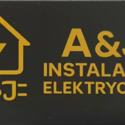 Żółte logo firmy A&J Instalacje Elektryczne na czarnym tle. Symbol domu z błyskawicą i napis 'INSTALACJE ELEKTRYCZNE'.