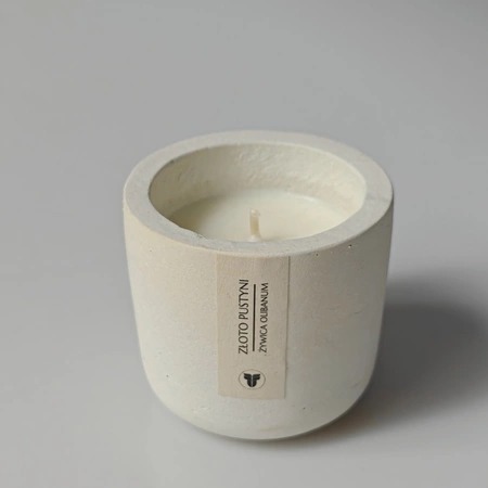 Beżowa świeca sojowa w betonowym pojemniku z etykietą 'Złoto Pustyni, Żywica Olibanum', minimalistyczny design, neutralne tło.