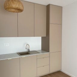 Las u Nas - Beżowa kuchnia na wymiar z drewnianą lampą. Umywalka w kolorze zabudowy, minimalistyczne uchwyty. Nowoczesny design, parkiet na podłodze.