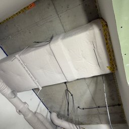 NEXTHOME KOVALEVYCH SPÓŁKA Z OGRANICZONĄ ODPOWIEDZIALNOŚCIĄ - Izolacja stropu wełną mineralną, zabezpieczona folią, widoczne przewody wentylacyjne i fragment płyty gipsowo-kartonowej. Prace wykończeniowe w trakcie realizacji.